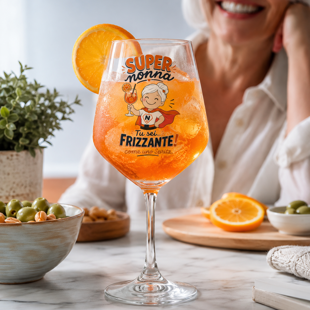 Calice in vetro con bevanda arancione, fetta d’arancia e scritta “SUPER nonna”