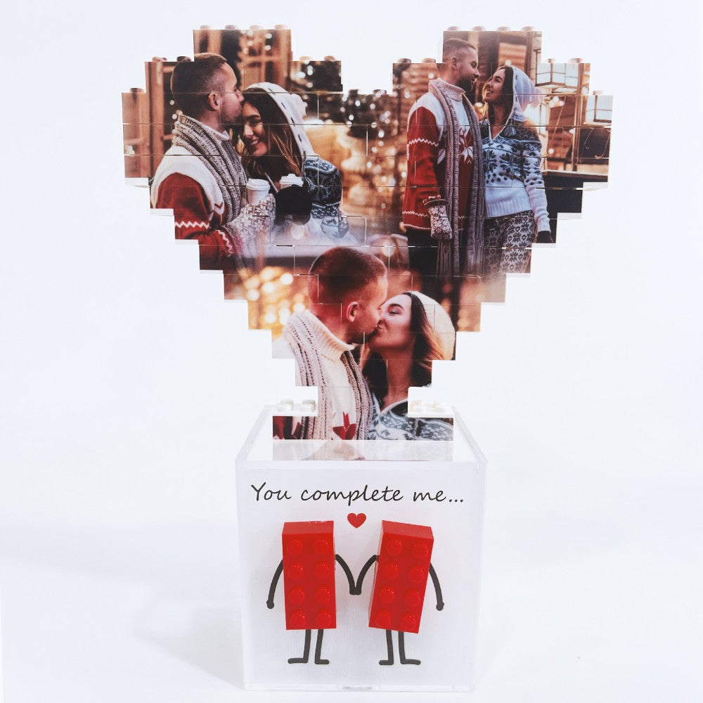 Cuore di foto in mattoncini sopra scatola bianca con due figure rosse stilizzate