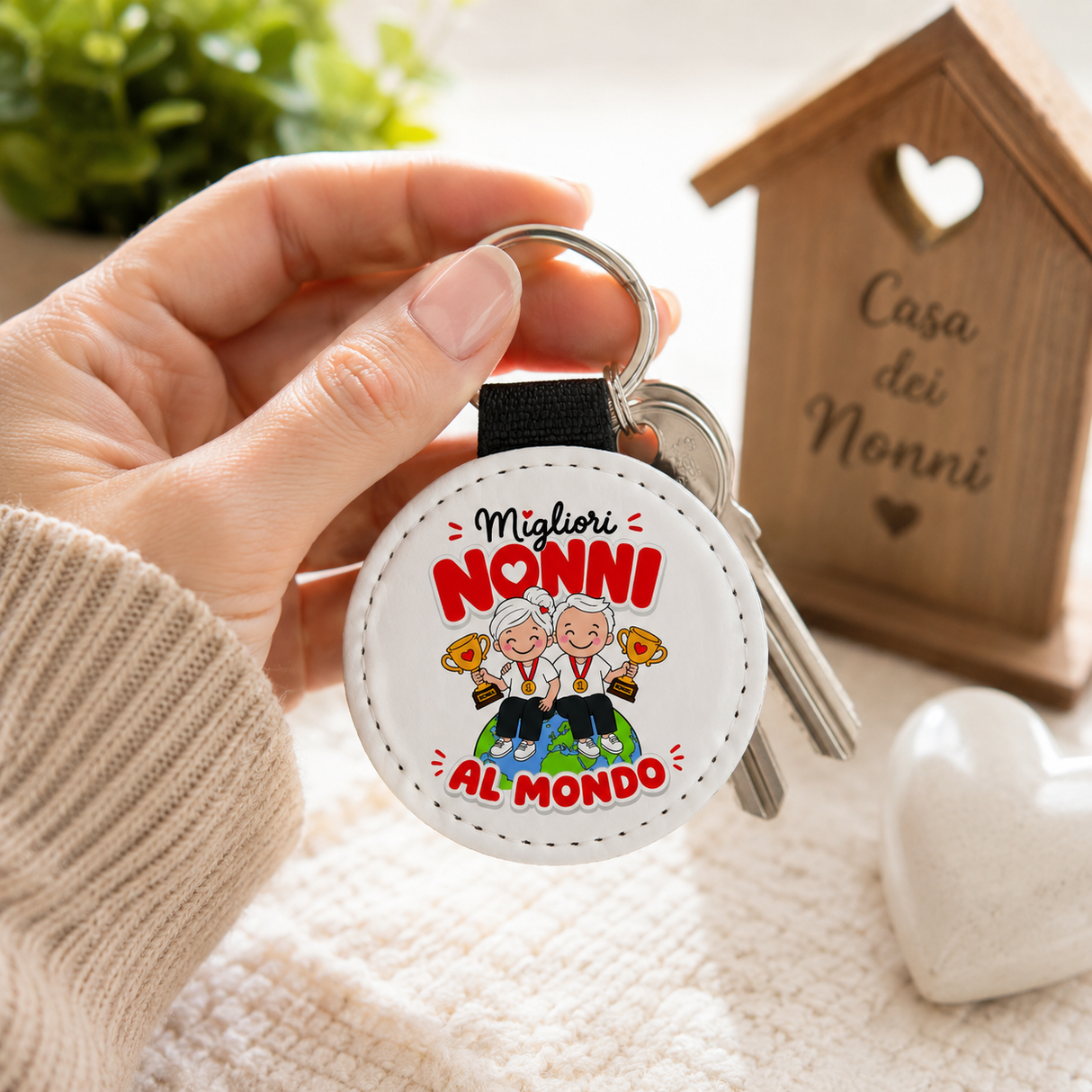 Portachiavi rotondo “Migliori Nonni al mondo” con cinturino nero, tenuto in mano