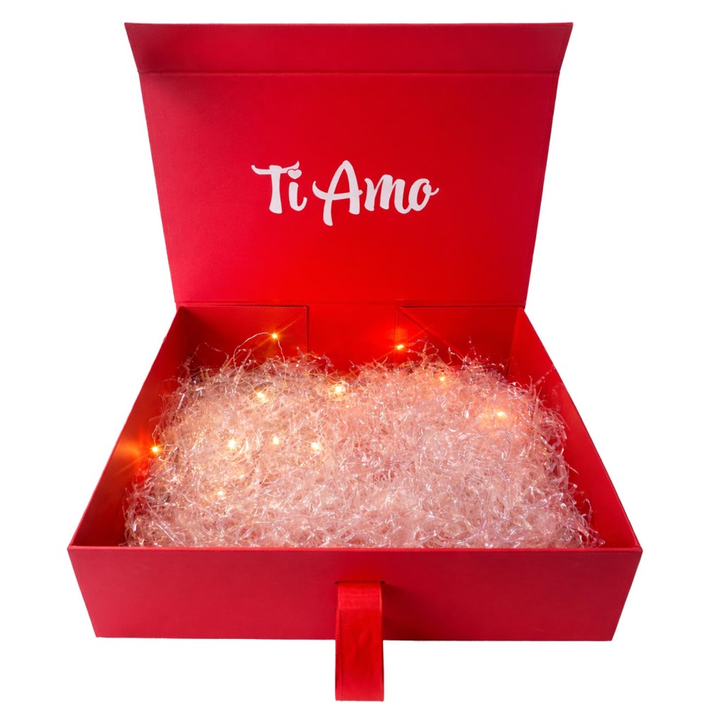 Scatola regalo rossa aperta con scritta “Ti Amo” e riempitivo rosa frantumato