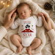 Body neonato natalizio bianco a maniche lunghe con stampa pinguino e scritta rossa.