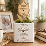 Vaso bianco con fiore in legno inciso e scritta “Nonni, voi siete le nostre radici”.