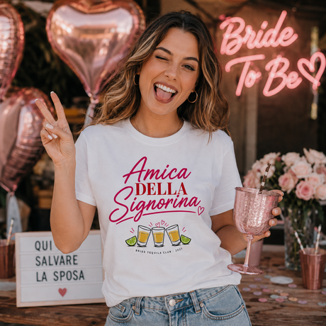 T-shirt bianca con scritta rosa “Amica della Signorina” e disegni di bicchieri tequila