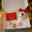 Confezione regalo aperta con pallina in vetro, biglietto rosso e timbro rosso