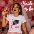 T-shirt bianca da sposa con stampa BRIDE e “prendo marito” rosa, indossata.