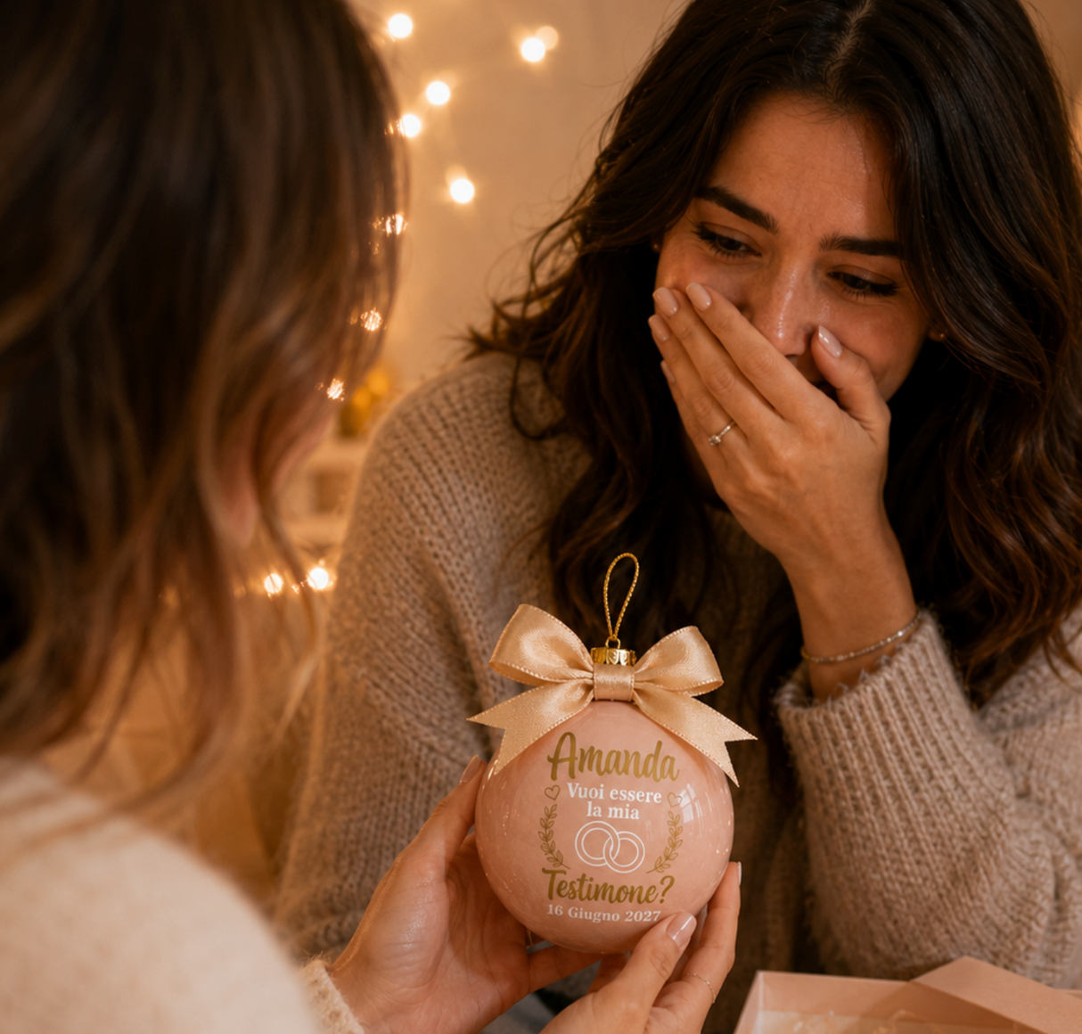 Pallina di Natale rosa in mano con fiocco dorato e “Vuoi essere la mia testimone?”