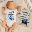 Body neonato bianco con controller e scritta blu "Nato per giocare con papà"