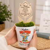 Vaso conico bianco con muschio verde e fiore in legno, tenuto tra le mani