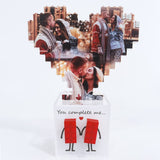 Cuore di foto in mattoncini sopra scatola bianca con due figure rosse stilizzate