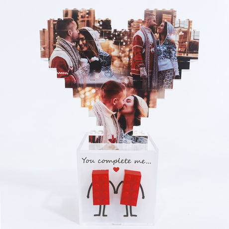 Cuore di foto in mattoncini sopra scatola bianca con due figure rosse stilizzate