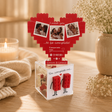 Cuore di mattoncini rosso con tre foto incorniciate, su supporto trasparente