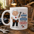 Tazza bianca con stampa del nonno e scritta, appoggiata su banco da lavoro.