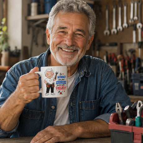 Tazza bianca con stampa del nonno e attrezzi, tenuta da un uomo in officina.