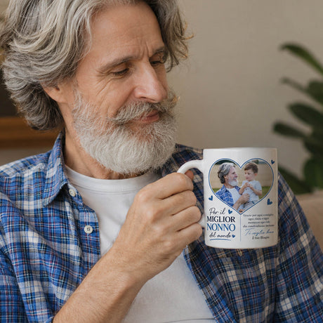Tazza bianca con grafica a cuore blu e dedica, tenuta da un uomo con barba.