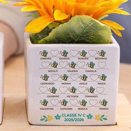 Vasetto bianco con fiori gialli, elenco nomi e 'CLASSE IV C 2025/2026' con api